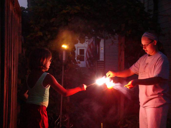 holly and meg starting their sparklers on the tiki torch....